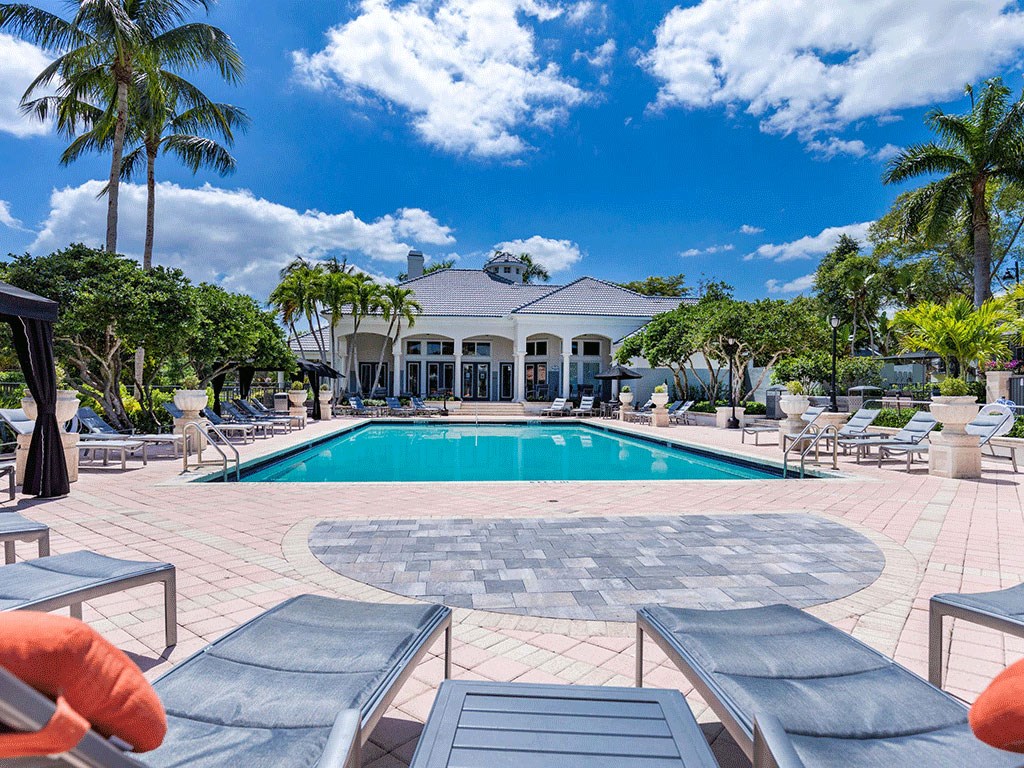 the pool is next to a large house with palm trees