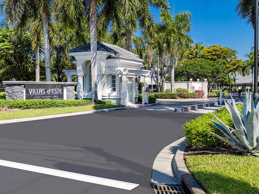 a driveway leading to a villa with palm trees