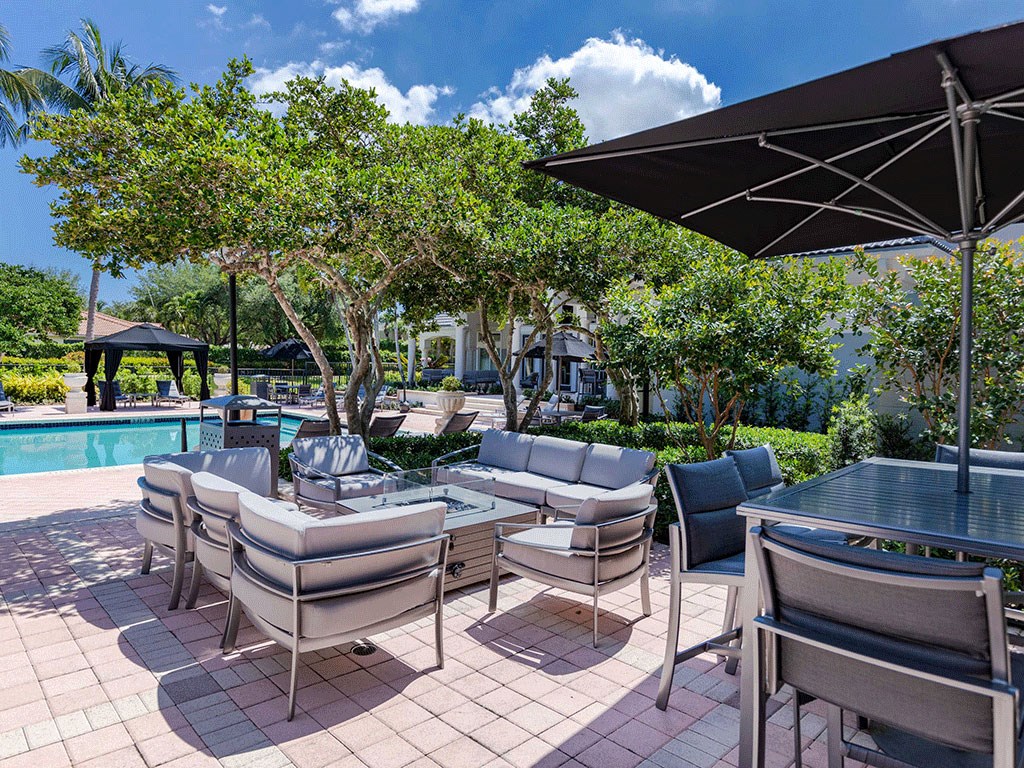 a poolside patio with chairs and tables and umbrellas
