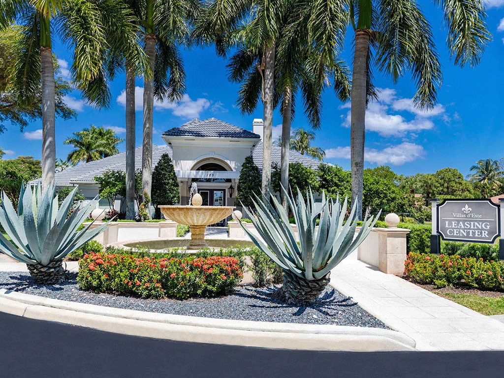 a fountain in front of a building with palm trees