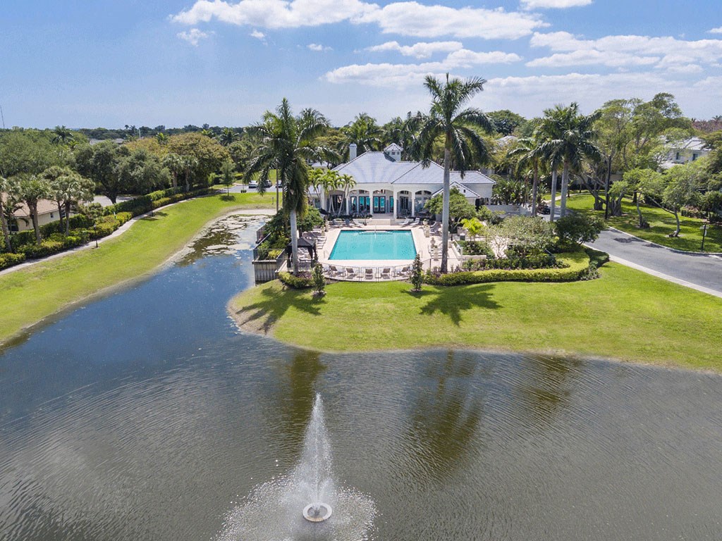 a mansion with a pool and palm trees on the water