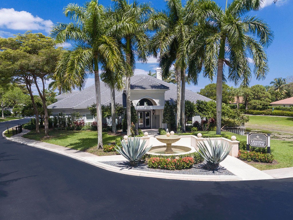 a fountain in front of a house with palm trees