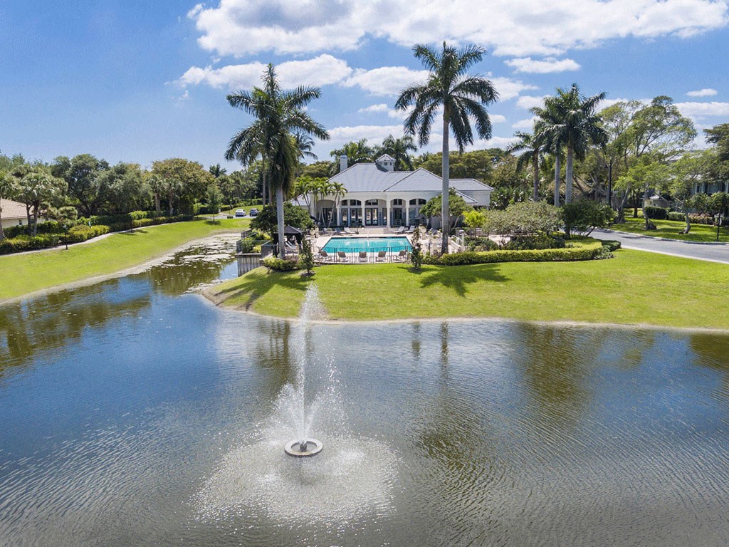a large house with a fountain in the middle of a pond