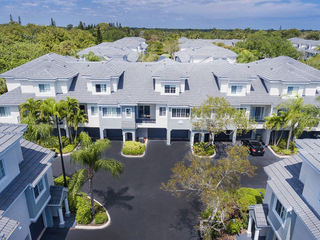 an aerial view of a large white building with palm trees