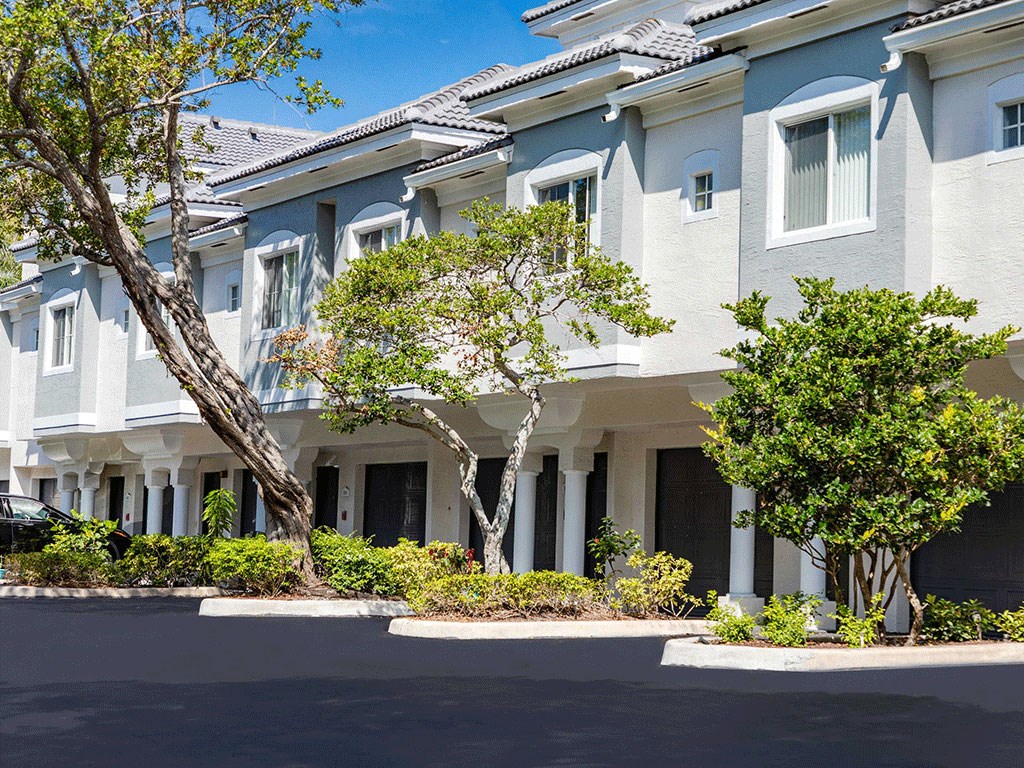 a row of white apartments with trees in front of them