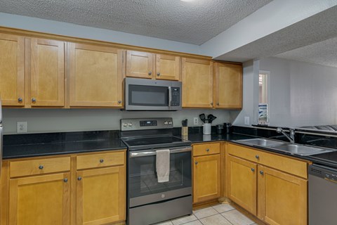 A kitchen with wooden cabinets and black countertops.