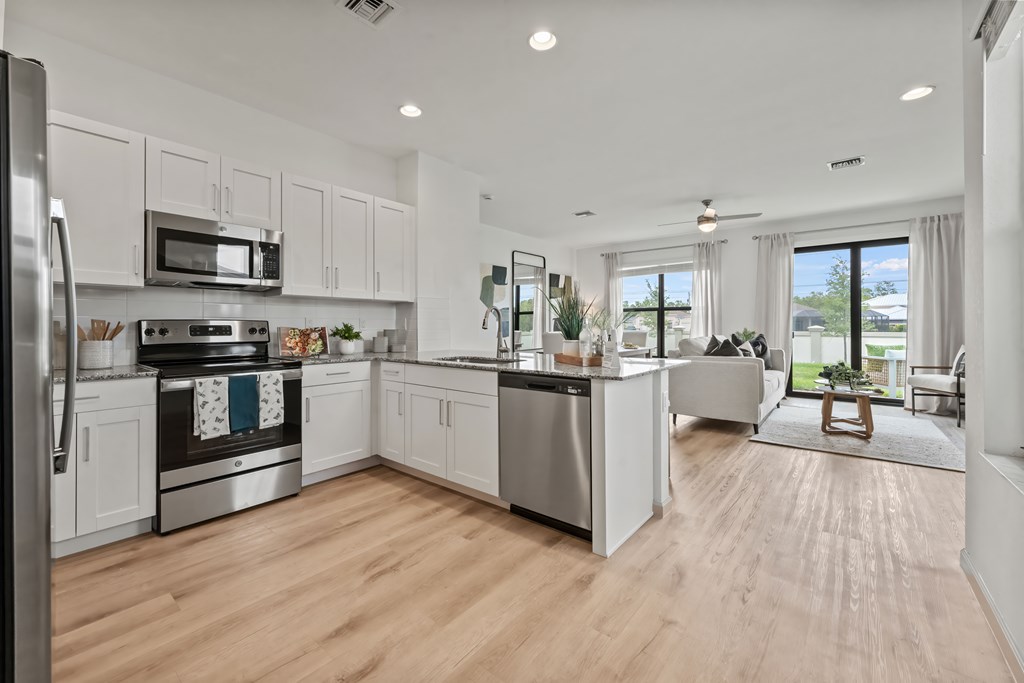 an open kitchen with white cabinets and stainless steel appliances