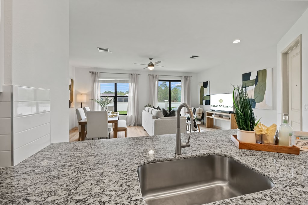 a kitchen with a sink and a view of a living room and a dining room