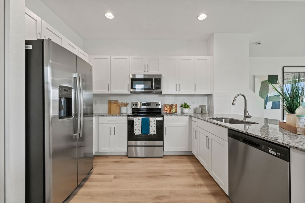 a large kitchen with stainless steel appliances and white cabinets