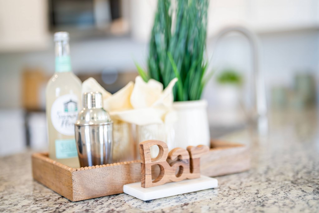 a wooden tray on a kitchen counter with a bottle and a candle