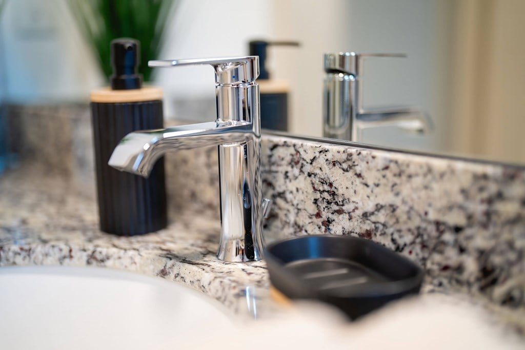 a bathroom sink with a silver faucet and a black soap dish