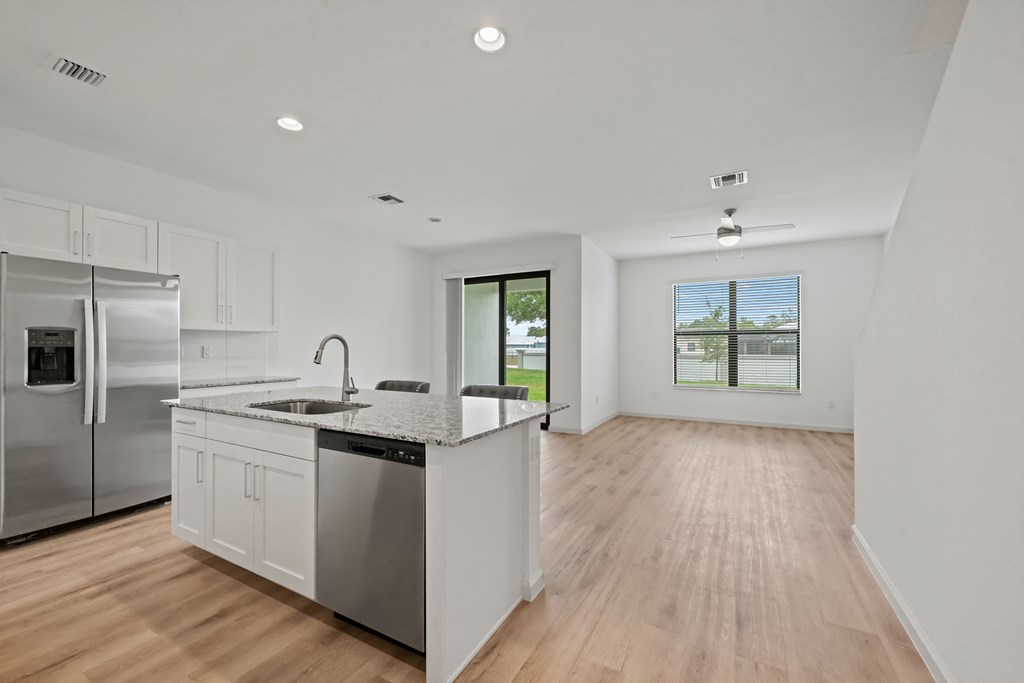 a large kitchen with an island and a stainless steel refrigerator