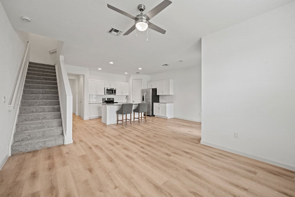 a living room with a staircase and a ceiling fan