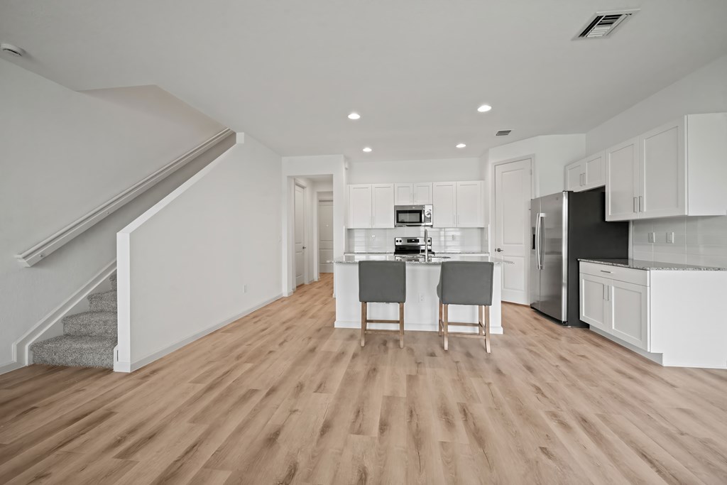 an open kitchen and living room with white cabinets and a kitchen island