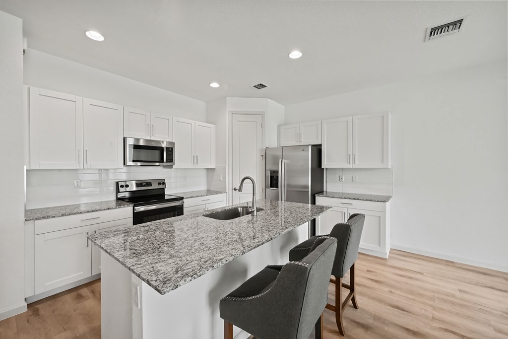 a kitchen with white cabinets and a marble counter top