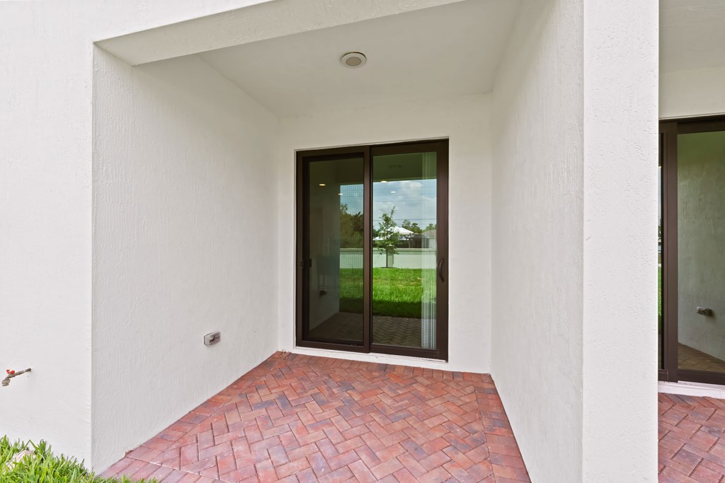 the entrance to a home with a red brick patio and glass doors