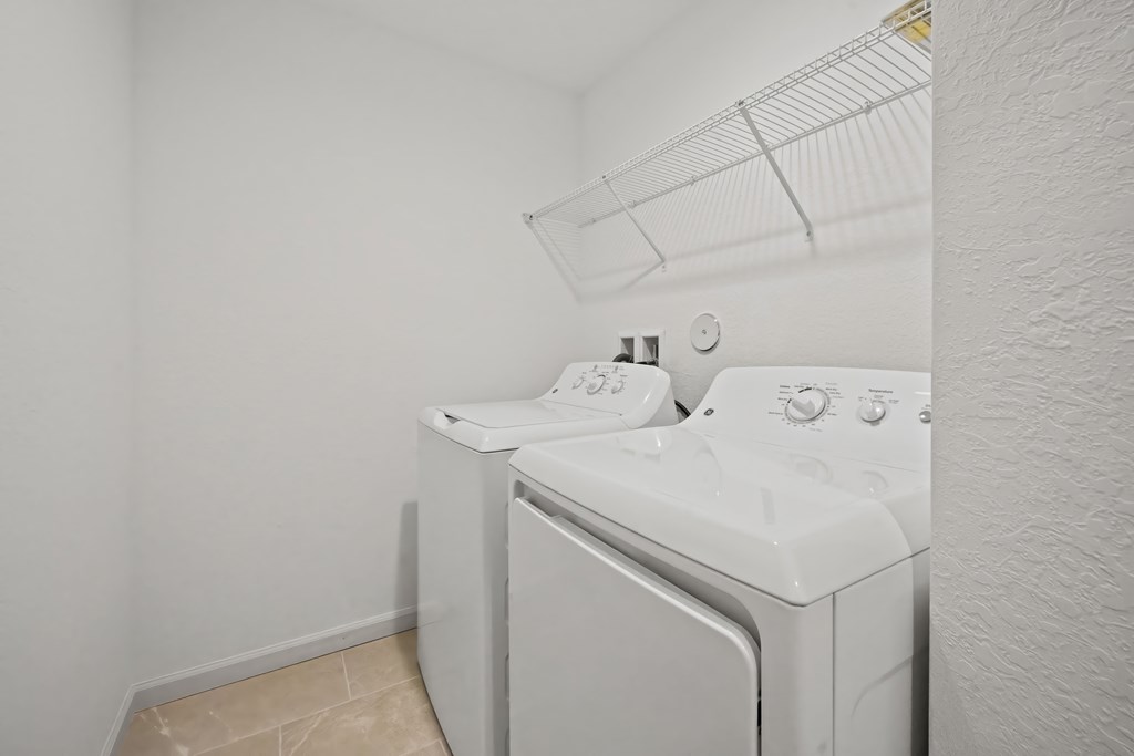 a washer and dryer in a laundry room with white walls and tile floor