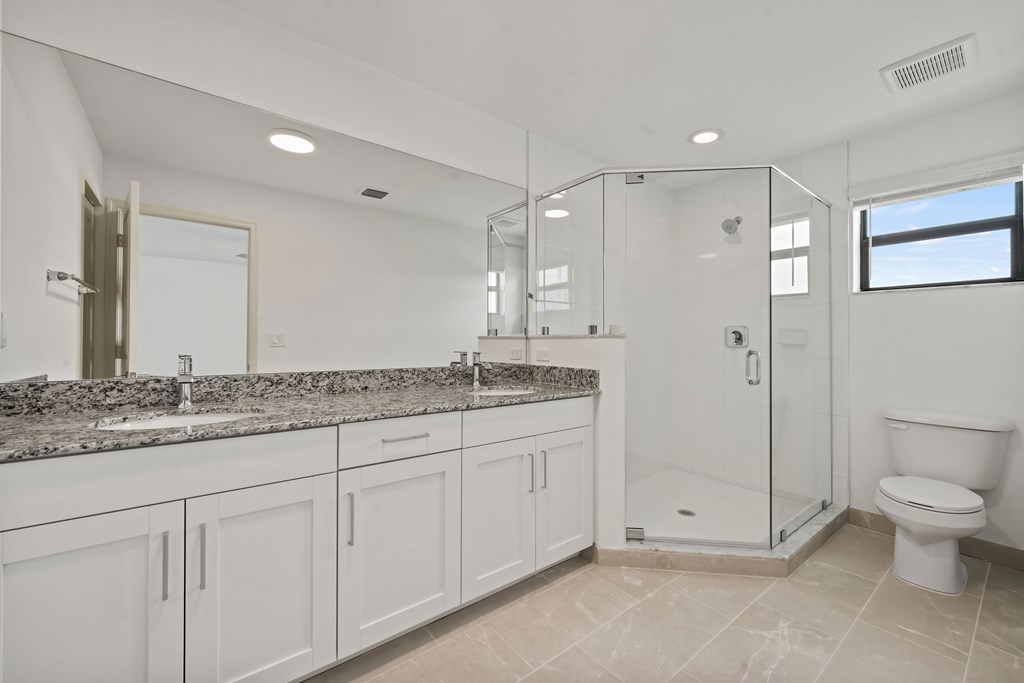 a bathroom with white cabinets and a shower and a toilet