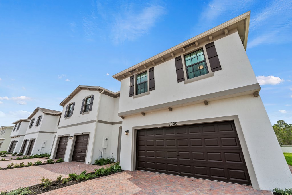 a group of white houses with brown garage doors