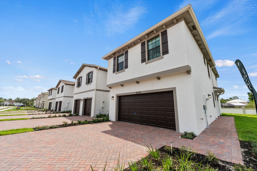 a group of white houses with a driveway and a garage