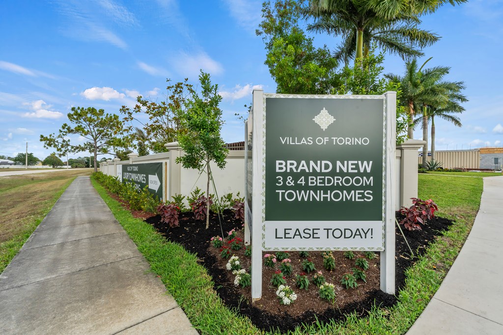 a sign for villas of tootoo in front of a sidewalk and trees