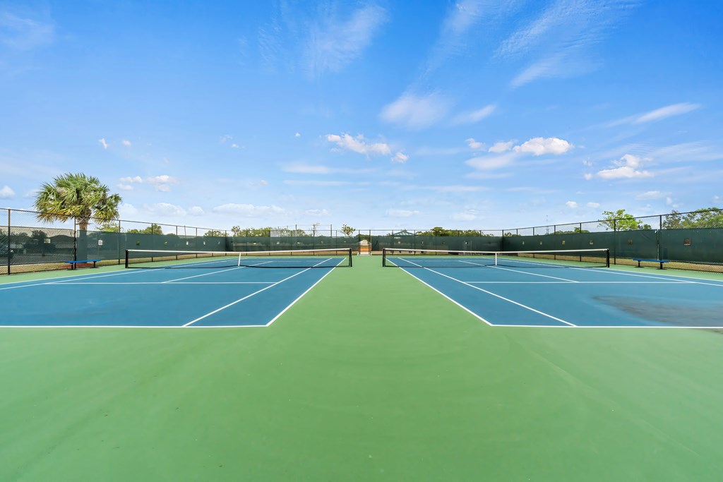 a tennis court with blue and green turf and a blue sky