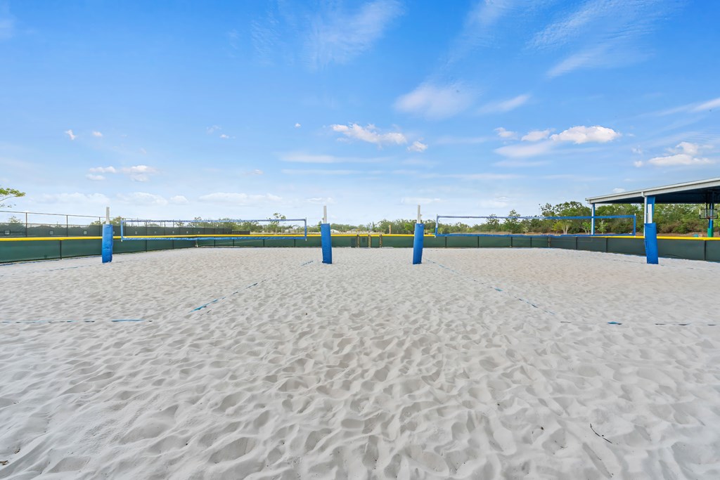 a sand volleyball court on a beach with blue posts