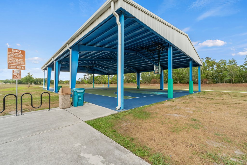 a covered park with a basketball court and a trash can