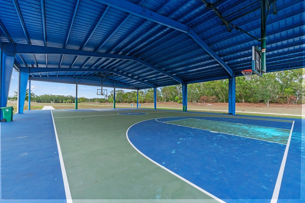 a basketball court under a blue roof at a park