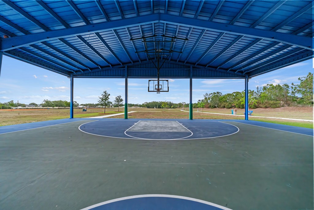 a basketball court with a blue roof in a park
