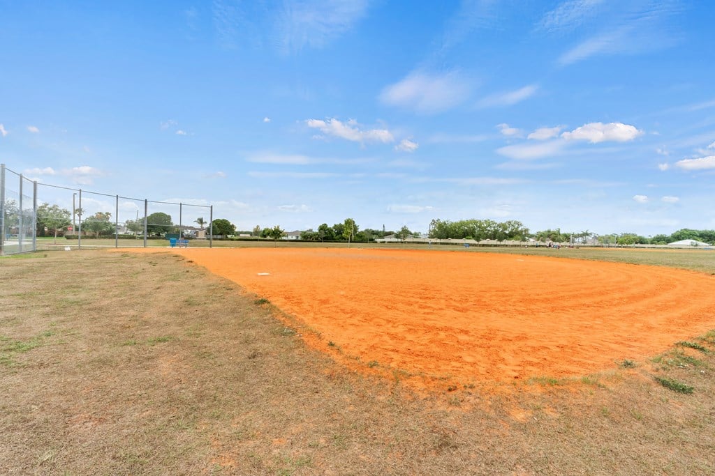 a baseball field with a chain link fence and a blue sky