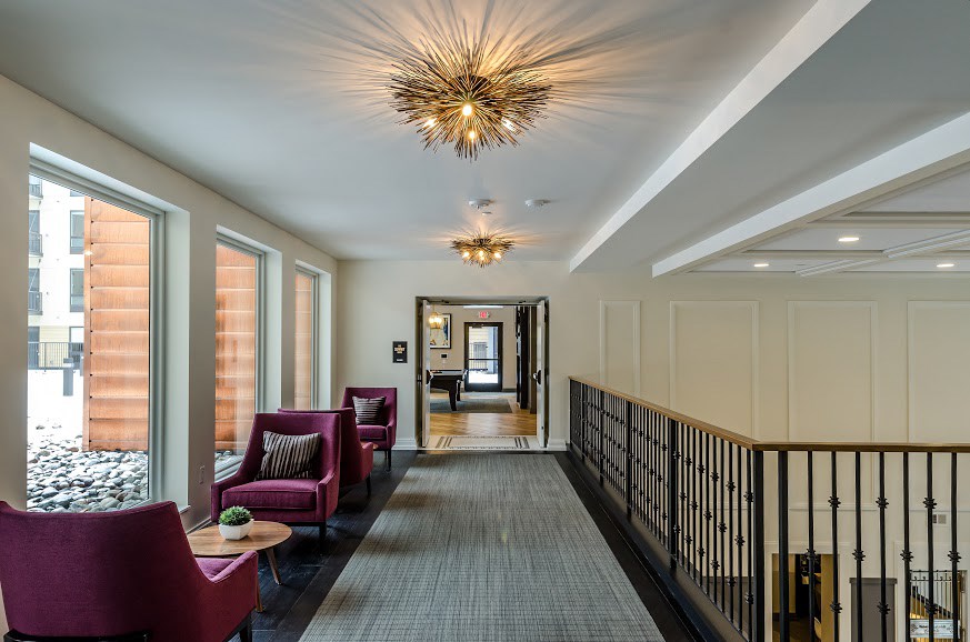 a lobby with chairs and a staircase and a chandelier