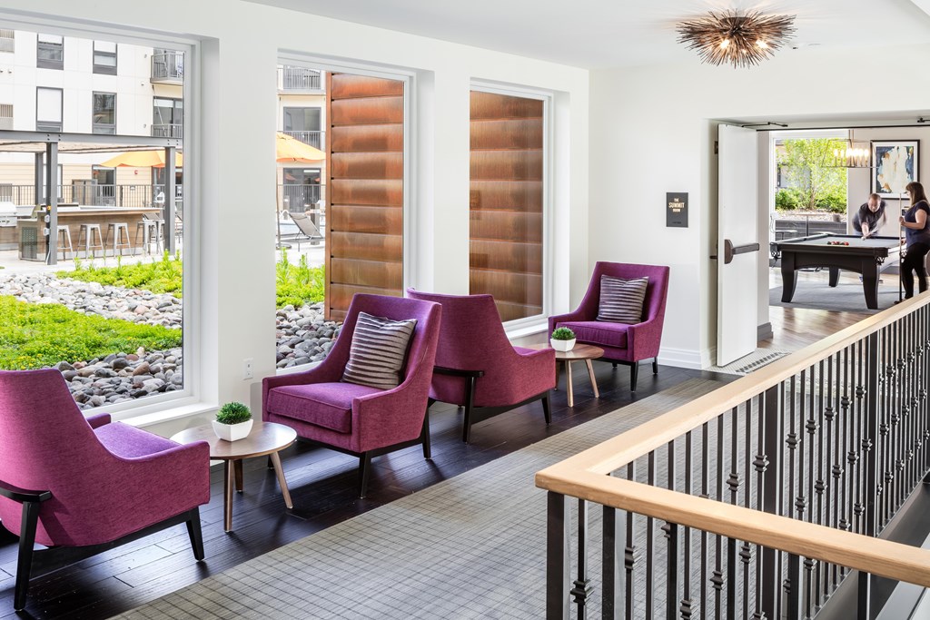 a living room with purple chairs and a balcony