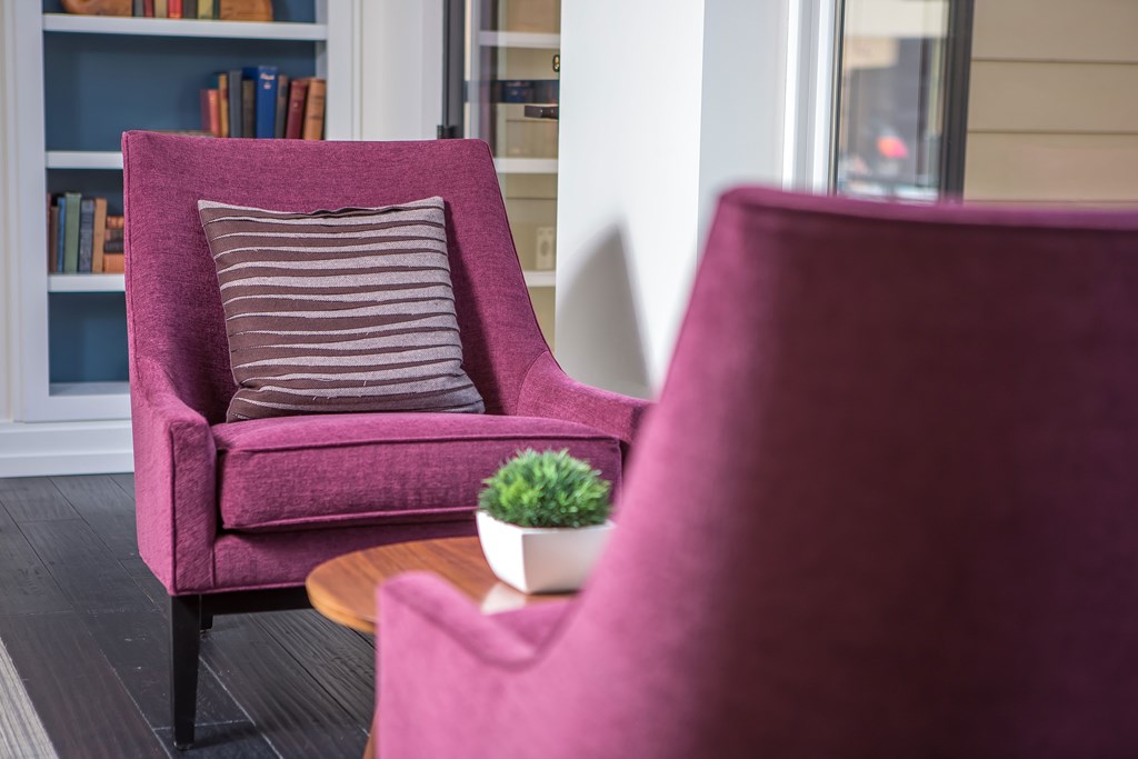a pair of purple chairs with a pillow and a plant on a table