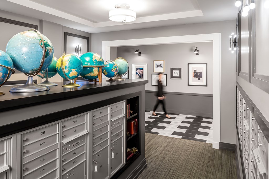 a hallway with a counter with globe displays on it and a person walking