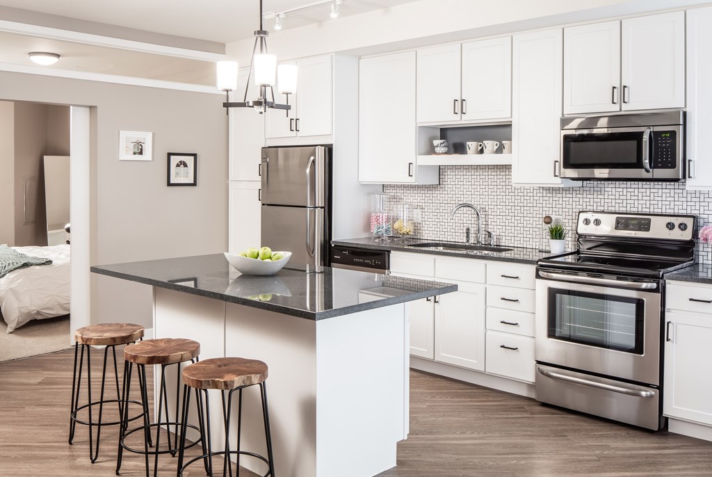a kitchen with stainless steel appliances and a counter with three stools