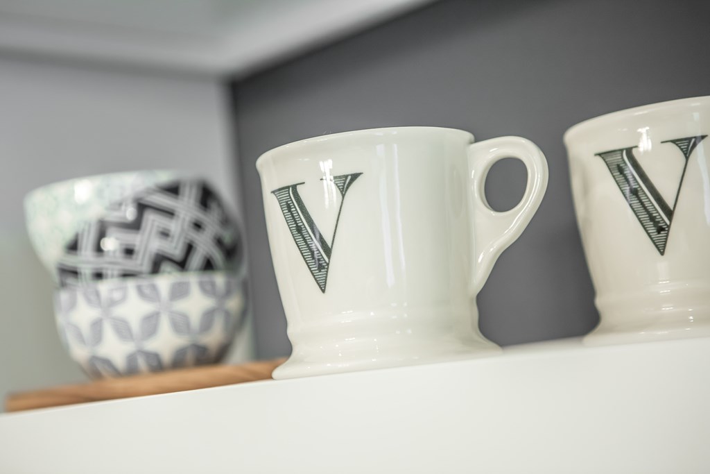 a white mug with a triangle on top of a shelf