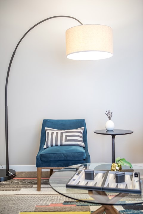 a living room with a blue chair and a table with a lamp