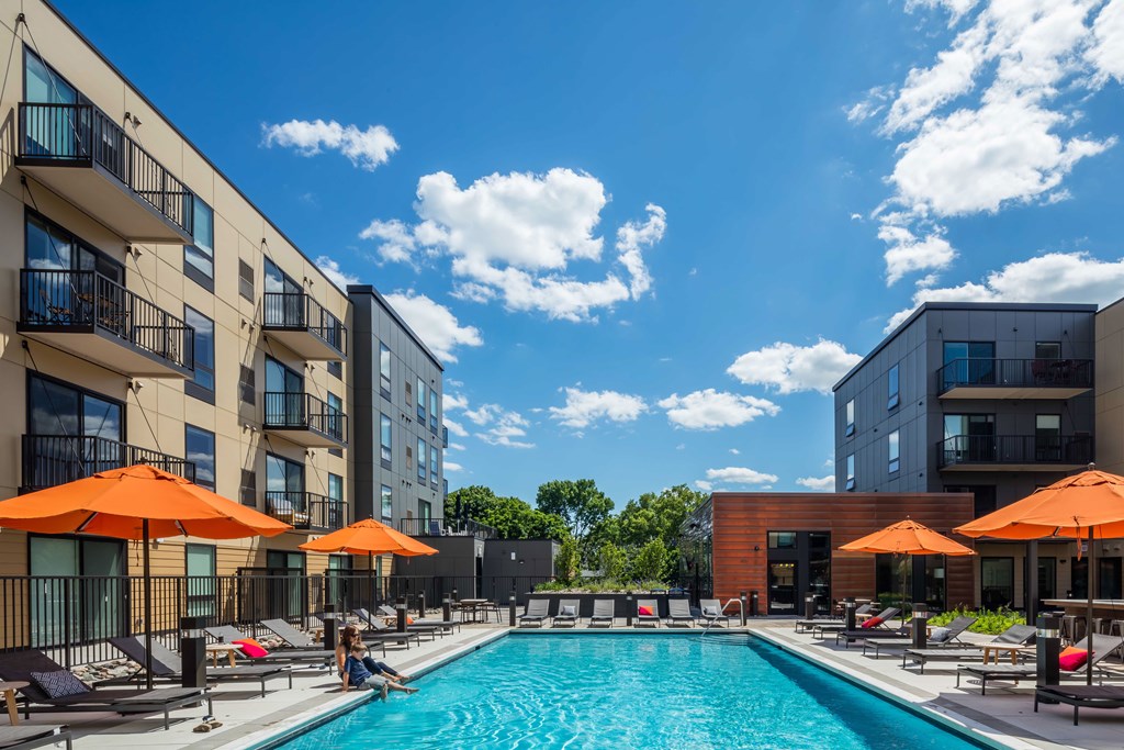 a swimming pool with umbrellas in front of some buildings