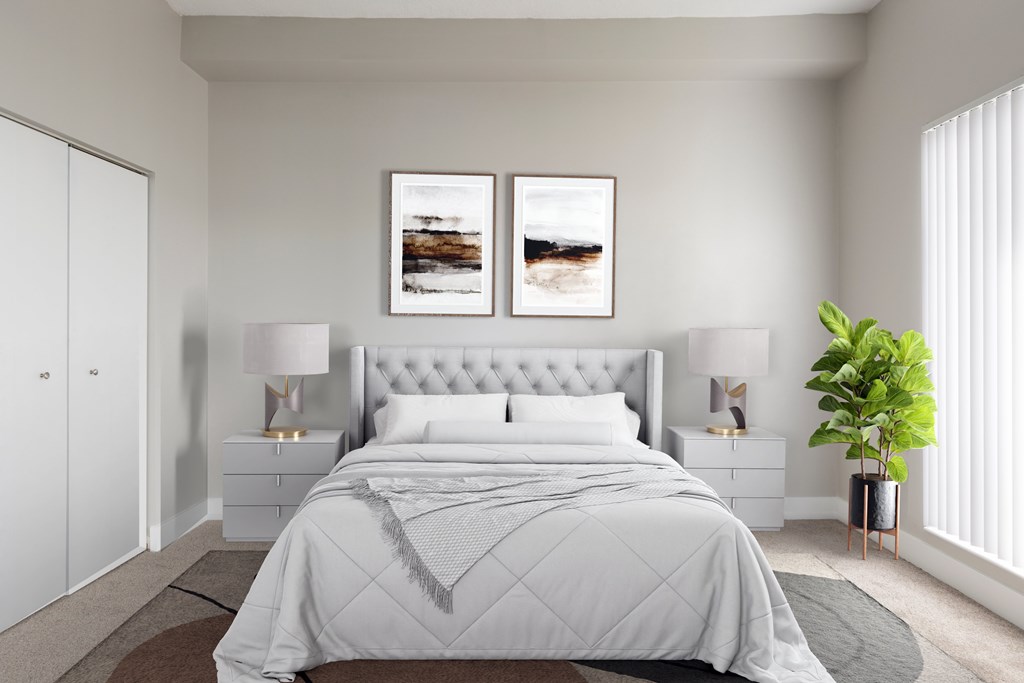 A bedroom with a large bed, two lamps, and two framed pictures on the wall.