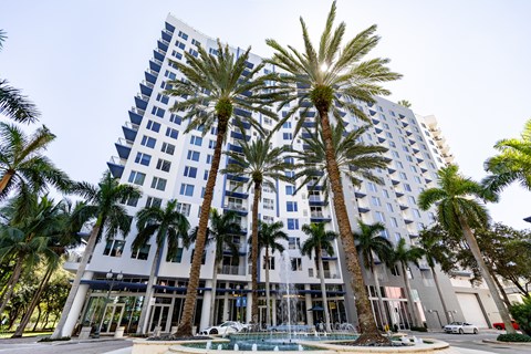 a tall building with palm trees in front of it and a pool