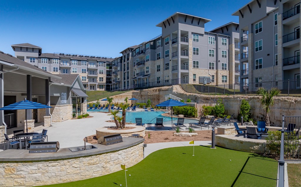 an apartment complex with a swimming pool and lawns with umbrellas