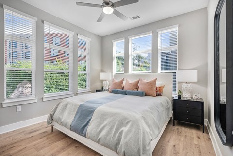 A bedroom with a bed, dresser, and a ceiling fan.