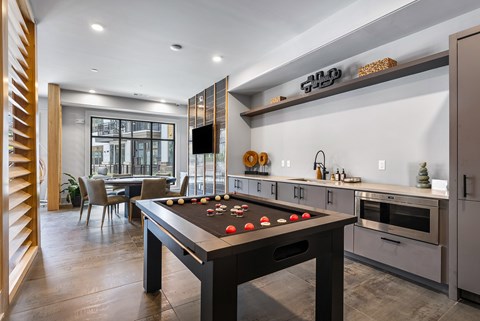 A pool table is in the middle of a kitchen and dining room.