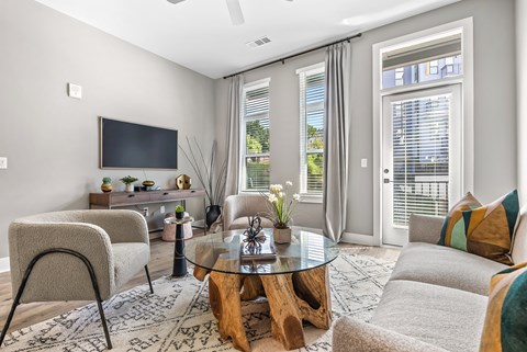 A modern living room with a glass coffee table and a flat screen TV.