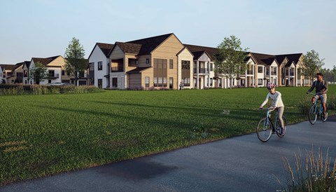 A person riding a bicycle on a path in front of a row of houses.