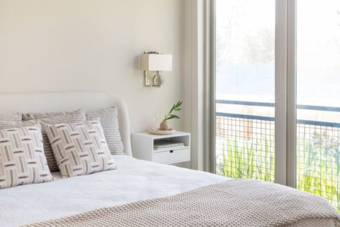 A bedroom with a large bed and a window overlooking a balcony.