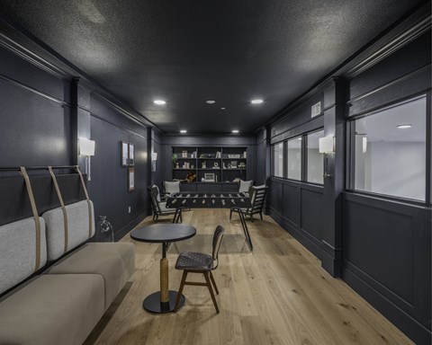 A modern living room with a grey sofa, a black table and a wooden floor.