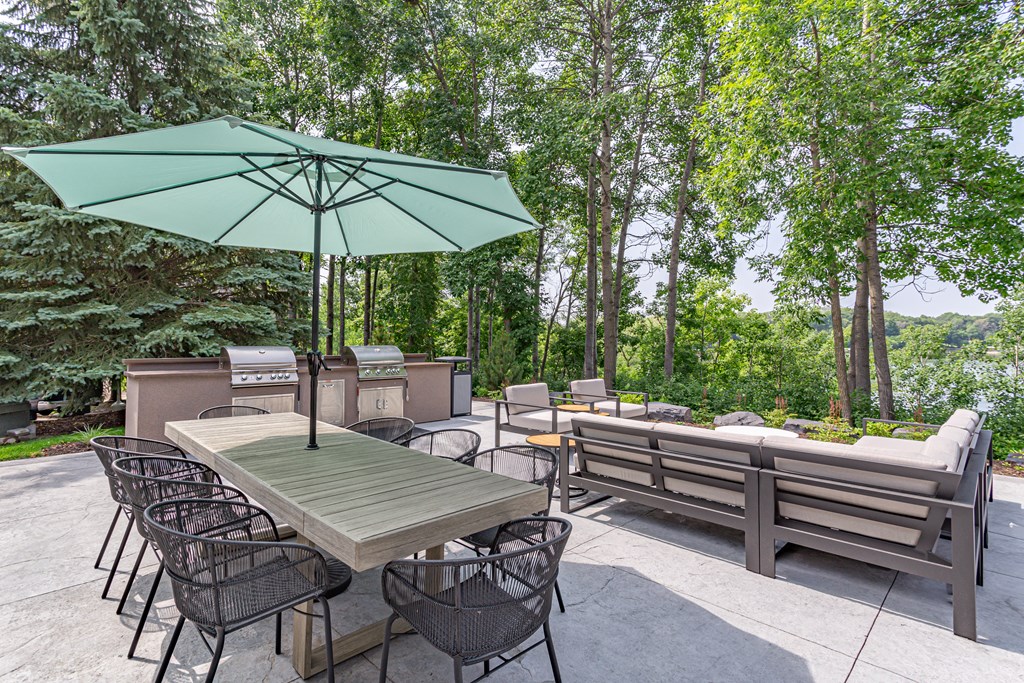 a patio with a table and chairs and a grill at Lake Susan Apartments in Chanhassen, MN