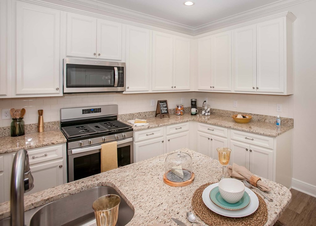 a kitchen with white cabinets and granite counter tops